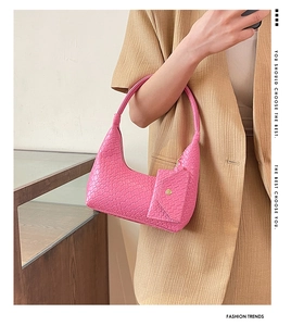 Detail of rose pink woven hobo bag with matching charm pouch on a stylish model outfit