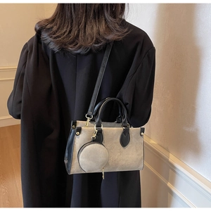 Detail of contrast beige canvas and black leather tote bag with a round mini pouch charm