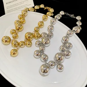 Irregular geometric metal ball fringe necklaces in gold and silver finish on a plate