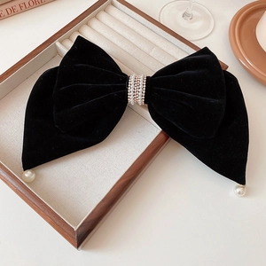 Détail d'un nœud en velours noir avec centre en strass et perles pendantes élégantes