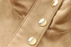 Macro shot of camel faux suede fabric texture and polished gold round button detail