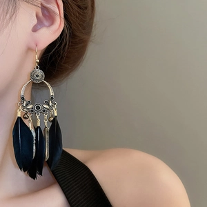 Détail de longues boucles d'oreilles bohèmes en plumes avec gravures dorées sur mannequin