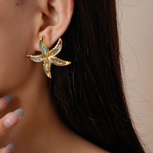 Detail of golden starfish earrings featuring iridescent abalone shell inlay for beach style