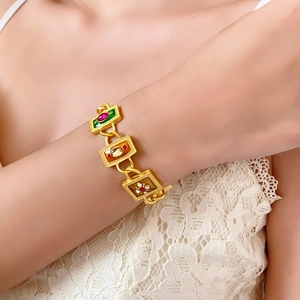 Detailed shot of vintage gold bracelet with red and green enamel charms and rhinestones