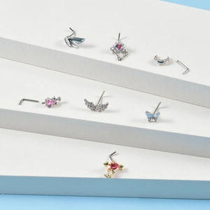 Macro detail of seven silver L-shaped nose studs with heart, moon and butterfly designs