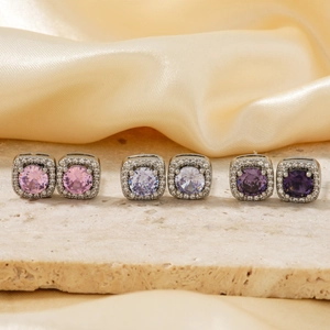 Square zircon stud earrings in pink and purple tones on a minimalist stone display