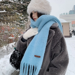 Sky blue long fringe wool-like scarf with minimalist brown leather patch in snowy scenery