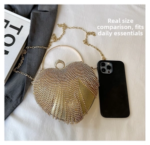 Macro shot of gold heart-shaped clutch bag with rhinestones next to a smartphone