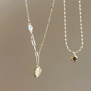Detail of gold bamboo oval necklace with white cat eye stone and brown gemstone pendant
