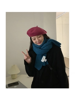 Close-up of peacock blue chunky knit scarf and burgundy wool beret on a model