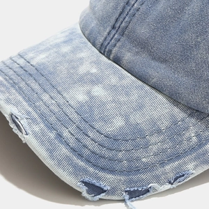 Close-up of distressed brim details and precision stitching on washed denim baseball cap