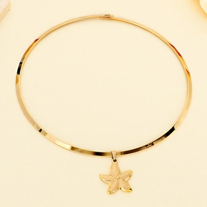 Detail of a rigid golden starfish pendant necklace on a textured sand-beige background