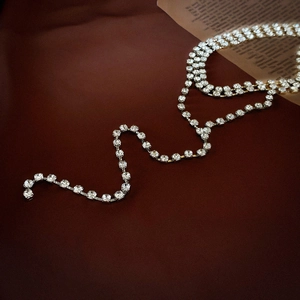 Macro di una collana d'argento con nappe e strass di cristallo su sfondo scuro scuro