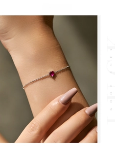 Detail view of s925 sterling silver bracelet with a red heart-shaped gemstone on wrist