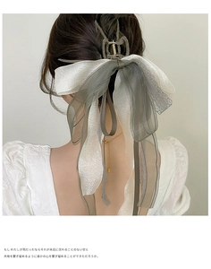 Rear view of a large grey and white tulle bow hair claw clip worn on hair with metal fringe