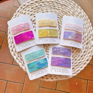 Five pairs of colorful laser glitter hair clips for kids on a white card display