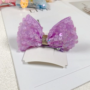 Detail of purple sequin mermaid bow hair clip with golden glitter center for girls