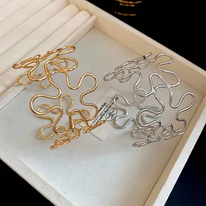 Minimalist wavy hollow metal bracelets in gold and silver finish displayed on a jewelry tray