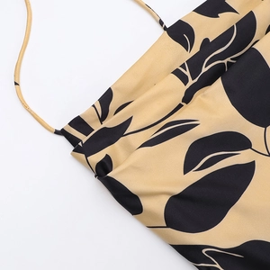 Close-up of yellow backless dress featuring black leaf print and delicate halter straps