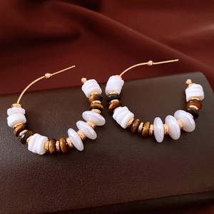 Détail macro de boucles d'oreilles C plaquées or 18 carats avec œil de tigre