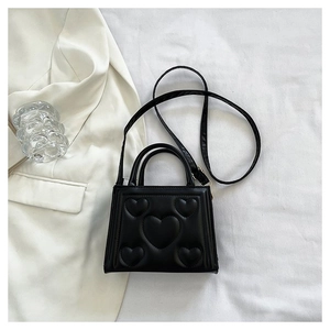 Détail du petit sac carré noir à motifs cœurs gaufrés avec bandoulière amovible et poignée