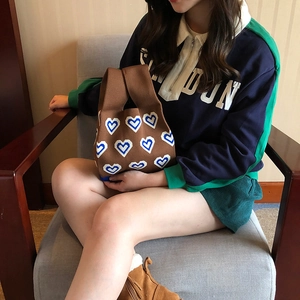 Detailed knit texture of brown tote bag with blue and white heart patterns on the fabric