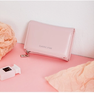 Nahaufnahme einer rosa Lederfalte Brieftasche mit Goldreißverschluss und Logo