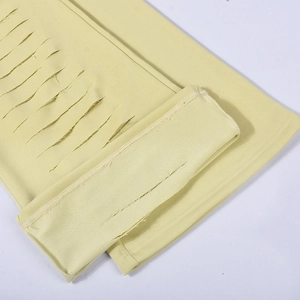 Detail of light yellow knit pants featuring trendy cutout designs and ribbed cuffs
