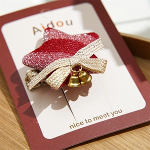 Detail of red glitter star hair clip with golden bow and bells on display card