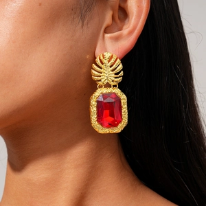 Detail of vintage gold palm leaf earring with faceted red rectangular gemstone