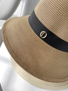Detail of woven straw hats with black grosgrain ribbon and golden metal hardware