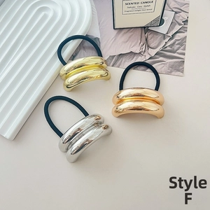 Detailed shot of double-layered metallic tubes in gold and silver on elastic hair ties