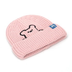 Pink knitted beanie with cute bear embroidery and blue label on a white background
