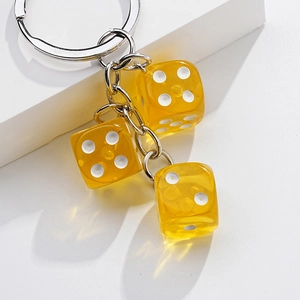 Macro shot of three yellow translucent dice pendants on a silver metal keychain