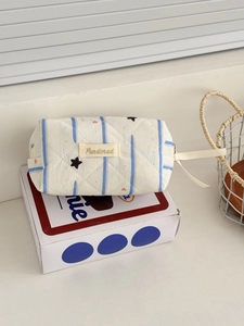 Detail of beige quilted makeup bag with blue stripes and tiny heart and star patterns