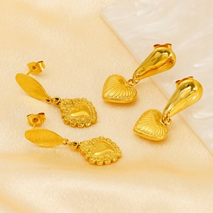 Détail de deux paires de boucles d'oreilles cœur dorées avec texture coquille et motifs