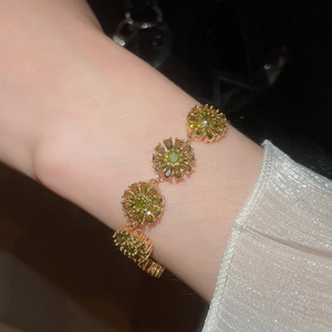 Detailed view of 18k gold plated bracelet with green heart zircon flower charms on wrist