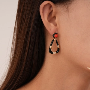 Macro view of vintage black enamel drop earrings with red stone and gold plating