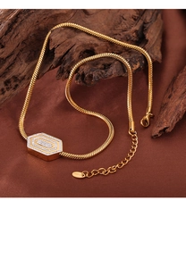 Dettaglio di una collana con ciondolo esagonale dorato e strass su legno e velluto