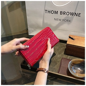 Close-up of red crocodile-pattern long leather wallet with shiny metal zipper detail
