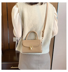 Rear view of model wearing a khaki retro mini crossbody bag with a beige knit vest