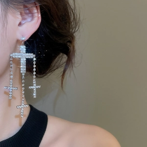 Detail of silver cross tassel earrings with sparkling crystals on a female model