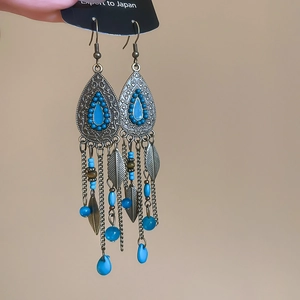 Detailed close-up of vintage silver earrings with blue beads and feather tassels