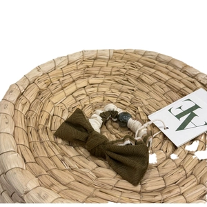 Elegant green ribbed bow scrunchie with bead detail on rustic straw background