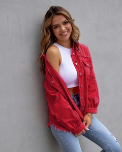 Detailed view of red denim jacket frayed edges and distressed texture on casual sleeve