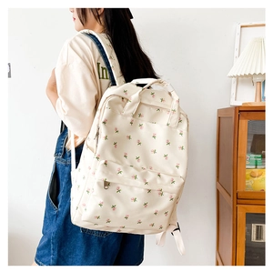 Girl wearing a cream floral canvas backpack in a cozy interior study room setting