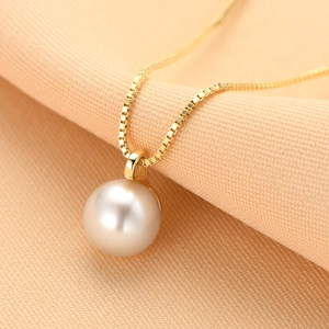 Macro shot of a high-luster white round freshwater pearl pendant with a fine gold box chain