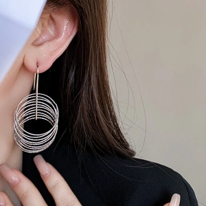Detail shot of multi-layered silver circular hoop earrings worn by a model