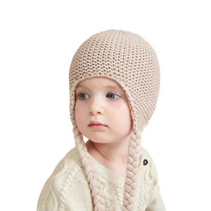 Detailed knit texture of pink baby earflap hat with braided tassels and soft yarn