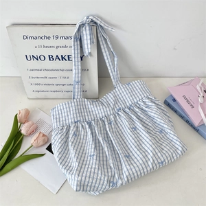 Close-up of blue plaid tote bag featuring delicate bow embroidery and pleated fabric detail